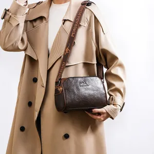 Detail view of the retro brown pillow crossbody bag, showcasing textured leather and wide strap.