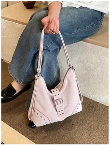 Detailed view of stylish pink shoulder bag with metal buckle and rivets for women.