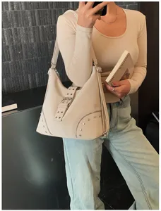 Detailed view of the chic beige shoulder bag with stylish front buckle and metal stud accents.