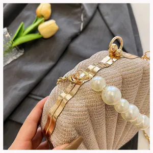 Gold shell evening bag featuring elegant pearl handle and metal kiss-lock closure design.