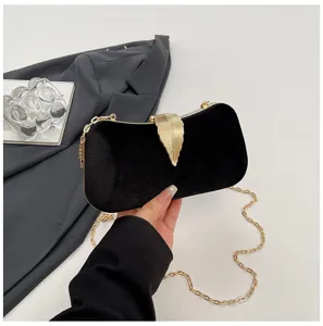 Black velvet evening clutch bag with gold leaf clasp and chain strap for special party.