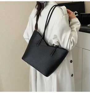 Detail view of a stylish black textured leather tote bag worn on shoulder, everyday commute use.