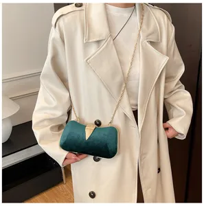 Elegant dark green velvet evening clutch bag with gold chain strap and chic leaf metal clasp.