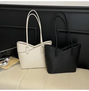 Detailed view of minimalist pebbled leather tote bags in black and white with dual straps.