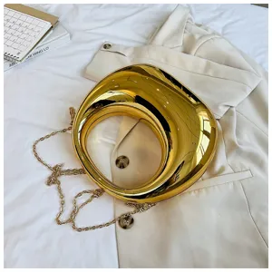 Primer plano detallado del exclusivo bolso cruzado rígido de color dorado con cadena.