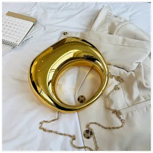 Detalle del bolso de mano escultural en oro metálico brillante con diseño moderno y cadena.