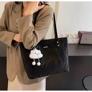 Detailed view of casual black tote bag with cute cloud pendant, stylish shoulder handbag.
