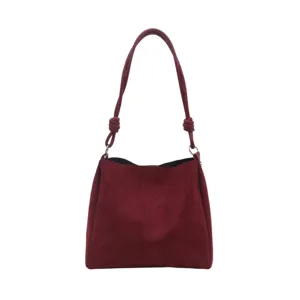 Close-up of the burgundy suede shoulder bag featuring a stylish knotted strap detail.