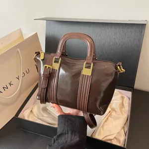 Vintage patent leather women handbag detail with gold metal buckles and top handle design.