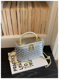 Detailed view of the silver metallic box crossbody bag with gold handle and studded surface texture.