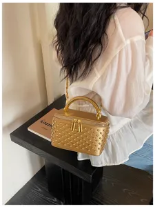 Gold metallic studded box shoulder bag detail, featuring top handle and chain strap for women.