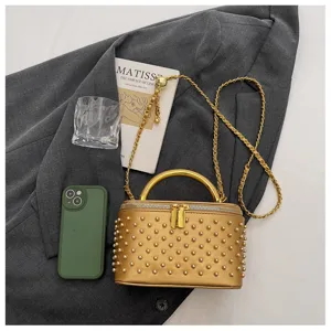 Detail view of the elegant gold studded box handbag with a top handle and chain strap.