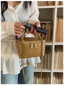 Gold studded vanity box bag detail shot, featuring metal handle and chic chain strap for women.