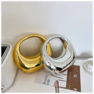 Primer plano de elegantes bolsos hobo de acrílico brillante metalizado en oro y plata.