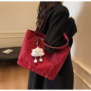 Detailed view of red patent leather tote bag featuring a cute white plush cloud charm.