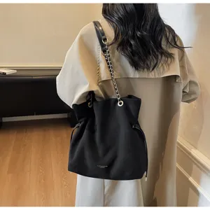 Sac cabas noir élégant avec bandoulière chaîne et cordon, porté par mannequin en gros plan.