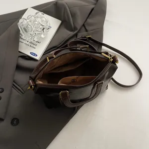 Vintage dark brown leather handbag detail view, featuring premium texture, dual top handles.
