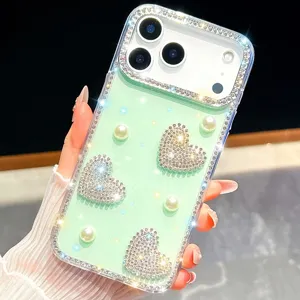 Detalle de funda de teléfono con corazón de estrás y perlas brillantes sobre fondo verde.