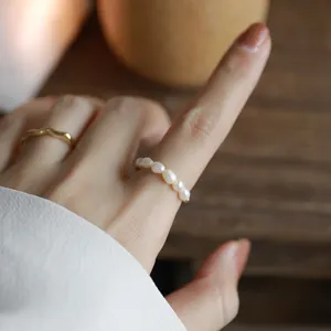 Close-up detail shot of dainty pearl elastic ring worn on finger, elegant minimalist style.