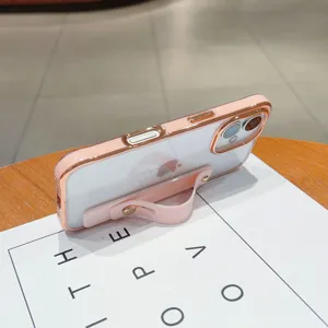 Detailed view of electroplated clear phone case featuring pink wrist strap and stand.