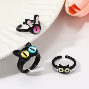 Nahaufnahme von süßen schwarzen Katzen und Monster Ringen mit bunten Katzenaugensteinen. Detail.