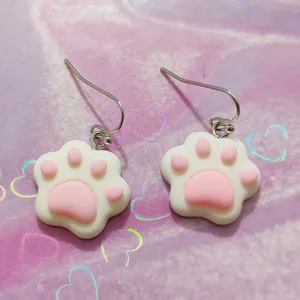 Close-up detail of cute pink and white resin cat paw drop earrings with metal fishhook wires.