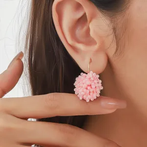 Gros plan détaillé de boucles d'oreilles boules de perles roses design floral.