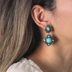 Close-up detail view of vintage bohemian turquoise gemstone drop earrings worn on earlobe.