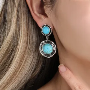 Close-up detail shot of vintage bohemian turquoise drop earrings, silver tone geometric design.