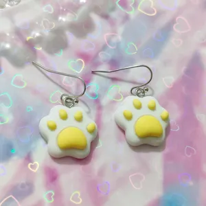 Close-up detail shot of cute resin cat paw dangle earrings, sweet dopamine style jewelry.