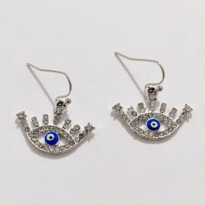 Close-up of silver rhinestone evil eye earrings featuring detailed blue enamel sparkle.