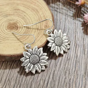 Boho vintage silver sunflower dangle earrings close up shot, detailed floral drop jewelry.