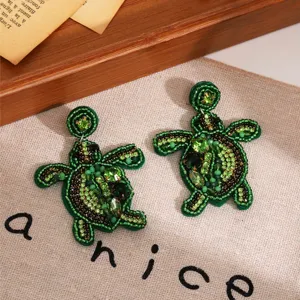 Gros plan sur des boucles d'oreilles tortue en perles faits main pour vos vacances d'été.