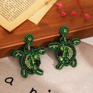 Gros plan détaillé de boucles d'oreilles tortue en perles vertes style plage.