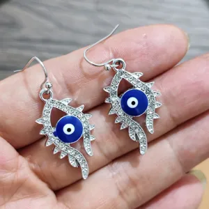 Stunning silver evil eye drop earrings featuring sparkling rhinestones and blue enamel details.