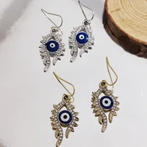 Detailed close-up of stylish evil eye dangle earrings with sparkling rhinestones in silver and gold.