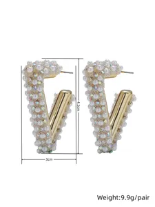 Close-up detail of geometric V-shaped earrings featuring faux pearls and crystal rhinestones.