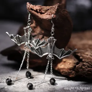 Close-up detail of gothic silver bat drop earrings with chains and black beads design.