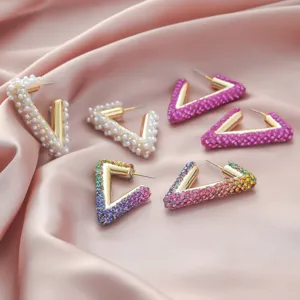 Detailed close-up view of fashionable geometric V-shaped rhinestone and pearl earrings set.