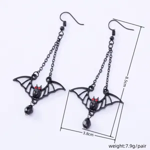 Close-up detail of gothic bat dangle earrings with black chains and red gemstone eyes.