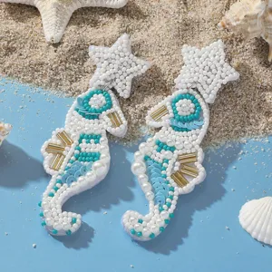 Dettaglio degli orecchini pendenti a forma di cavalluccio marino con perline e paillettes.