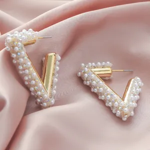 Close-up of geometric V-shaped pearl rhinestone earrings detail showcasing luxury style.