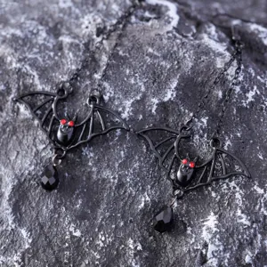 Gothic bat earrings detail shot featuring black metal chains and red rhinestone eyes.