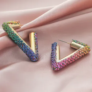 Close-up detail of geometric V-shaped earrings featuring vibrant gradient crystal rhinestones.