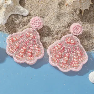 Vista dettagliata di orecchini a conchiglia con perline rosa con sabbia da spiaggia e stella.