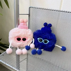 Close-up detail of cute plush AirPods case featuring fluffy character with knit hat sunglasses.
