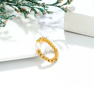 Close-up of a minimalist gold beaded ring with a natural freshwater pearl, elastic daily accessory.