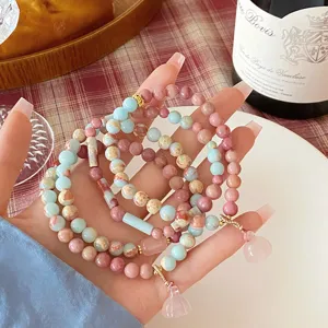 Detail shot of stacked beaded gemstone bracelets with crystal lotus and gourd pendants.