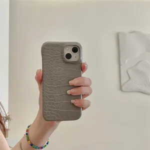 Vista detallada de la funda de teléfono con textura de cocodrilo gris en la mano.