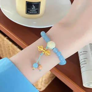 Charming light blue natural stone bracelet with delicate gold charm and white flower bead detail.